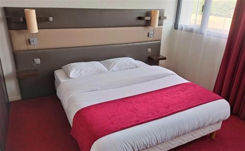 een slaapkamer met een groot bed en een rode deken bij Résidence Hôtelière des Ondes in Saint-Lys