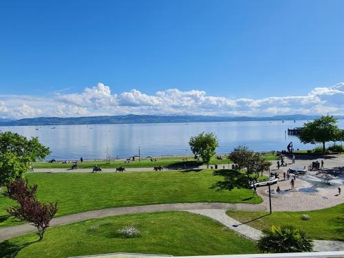 eine Gruppe von Menschen, die in einem Park neben einem Wasserkörper spazieren in der Unterkunft Gästehaus Seeblick in Langenargen