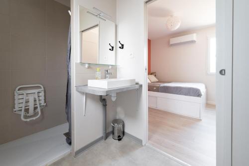 a bathroom with a sink and a mirror and a bed at Lot en Dock 3 logements atypiques et écologiques en vallée de la Dordogne in Souillac