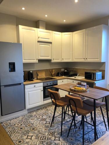 une cuisine avec des armoires blanches et une table et des chaises dans l'établissement Le Saint Rémy by Sparnapart, à Épernay