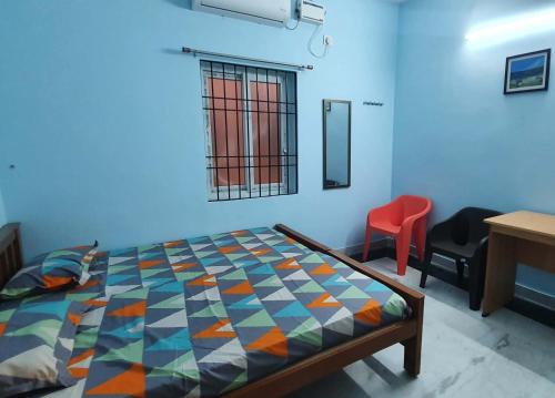 a bedroom with a bed and a red chair at Sunshine Stay in Chennai