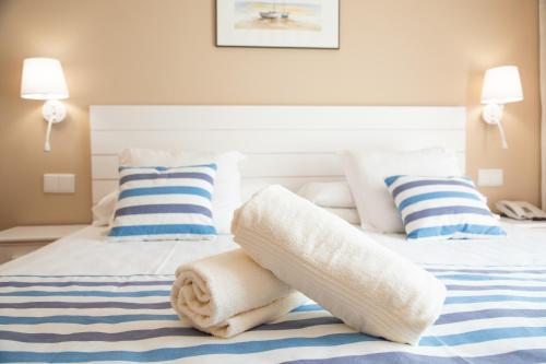 a bed with white towels and pillows on it at Hotel Dwo Les Palmeres in Calella