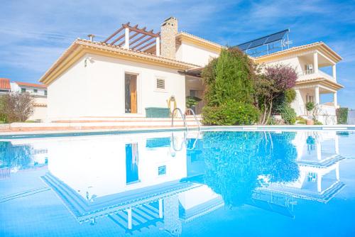 a villa with a swimming pool in front of a house at Villa Alegre in Fernao Ferro
