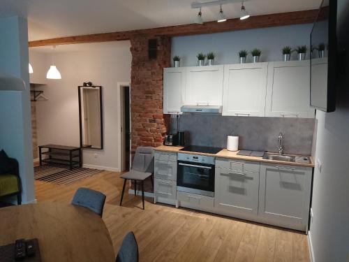 a kitchen with white cabinets and a table and chairs at Miško Apartments in Šilutė