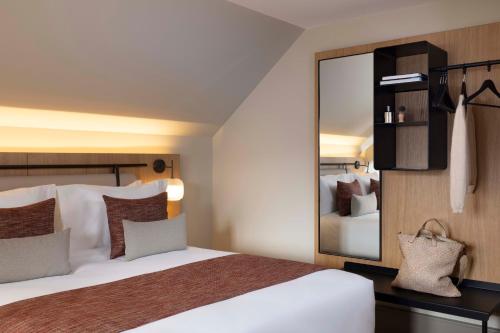 a bedroom with a bed and a large mirror at Hotel La Diligence in Obernai