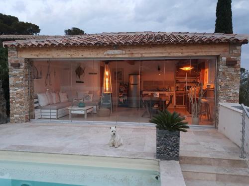 un chien assis sur une terrasse à côté d'une maison dans l'établissement VILLA REVA 3 CHAMBRES, aux Issambres