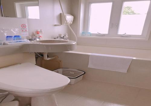 a bathroom with a toilet and a sink and a window at Tenshino Iruka in Ito