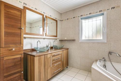 une salle de bain avec deux lavabos et une baignoire dans l'établissement Maison avec piscine pour 6 personnes, à Les Sables-dʼOlonne