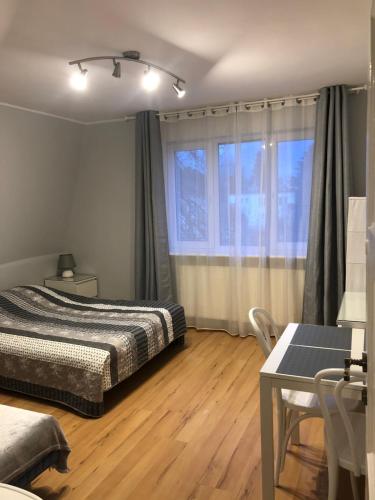 a bedroom with a bed and a desk and a window at Noclegi Gdańsk Pokoje Gościnne in Gdańsk