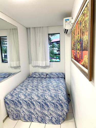 a small bedroom with a bed and two windows at Flat Marulhos Resort in Porto De Galinhas