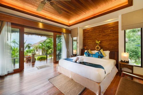 Un dormitorio con una cama grande y puertas corredizas de vidrio. en The Beach Natural Resort Koh Kood, en Ko Kood