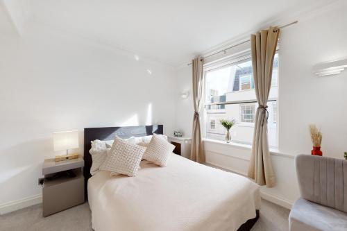 a white bedroom with a bed and a window at Stay in bond street in London