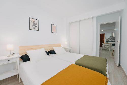 ein weißes Schlafzimmer mit einem großen weißen Bett und einem Zimmer in der Unterkunft Top2Stay Alhóndiga in Málaga