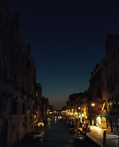 a city at night with boats in the water at B&B Cà del Poeta in Venice