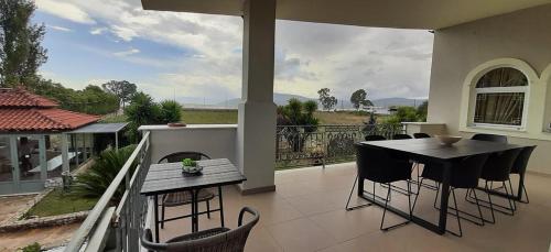 a patio with a table and chairs on a balcony at The Villa of the Winds in Néa Kíos