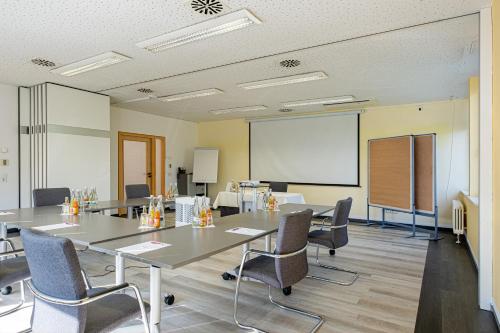 a conference room with a table and chairs and a whiteboard at Hotel Am Froschbächel in Bühl