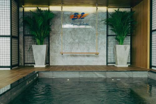 a swimming pool with two potted plants in a room at BE Baan Paradise Hotel in Patong Beach