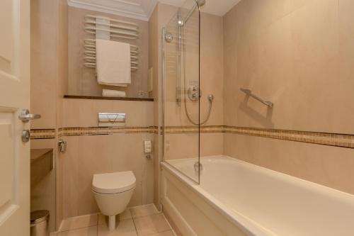 a bathroom with a tub and a toilet and a shower at Western House Hotel At Ayr Racecourse in Ayr
