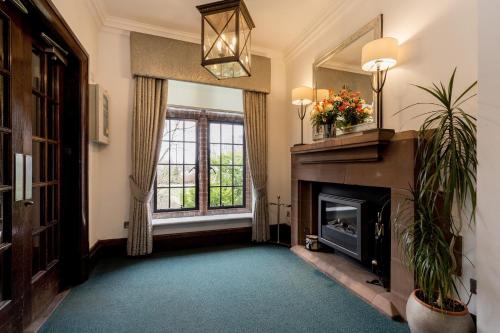 a living room with a fireplace and a window at Western House Hotel At Ayr Racecourse in Ayr