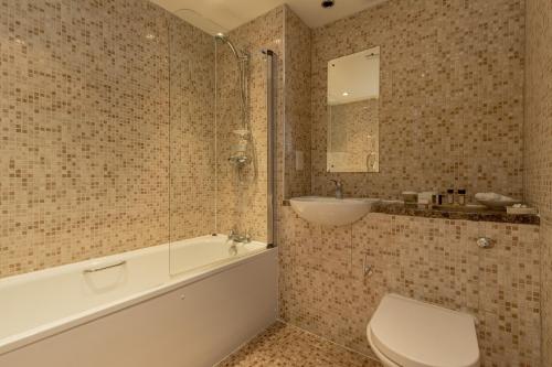 a bathroom with a tub and a toilet and a sink at Western House Hotel At Ayr Racecourse in Ayr