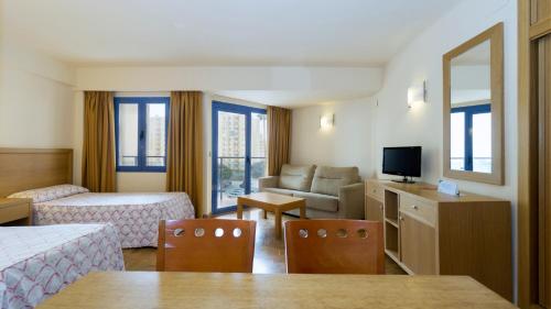 ベナルマデナにあるApartamentos MS Pepitaのベッドとリビングルームが備わるホテルルームです。