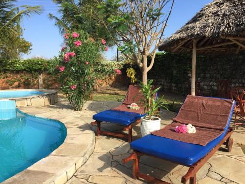 two chairs and a table next to a swimming pool at MASKANI Villa in Galu