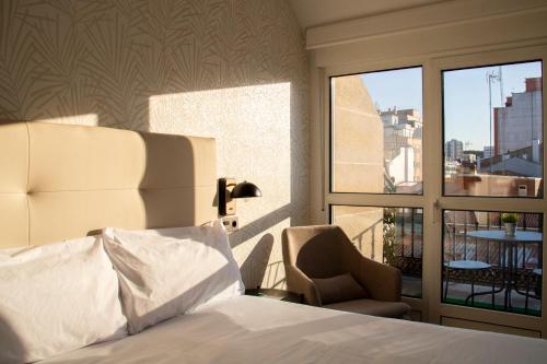 a bedroom with a bed and a chair and a window at Alda Orzán in A Coruña