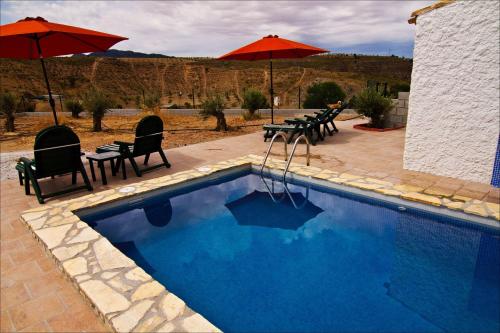 a swimming pool with chairs and umbrellas next to a patio at Cueva Pura Vida in Pulpite