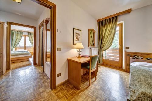 a bedroom with a desk and a bed and a window at Hotel Piccolo Pocol in Cortina dʼAmpezzo