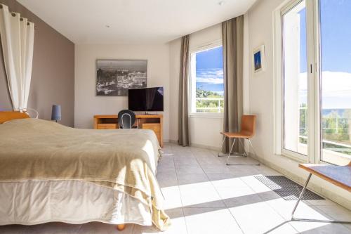 une chambre avec un lit, une télévision et des fenêtres dans l'établissement Villa Lili Rose, au Lavandou