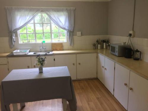 cocina con mesa, fregadero y ventana en Meshlynn farm cottage, en Thendele