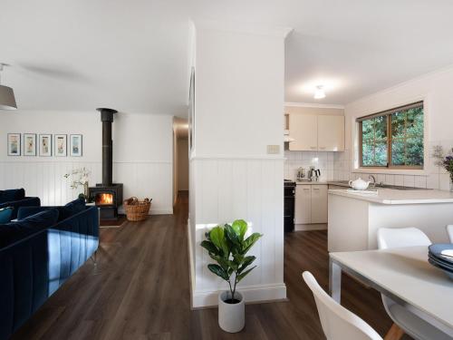 a kitchen and living room with white cabinets and a table at Springview Cottage- captivating bush retreat in Hepburn Springs