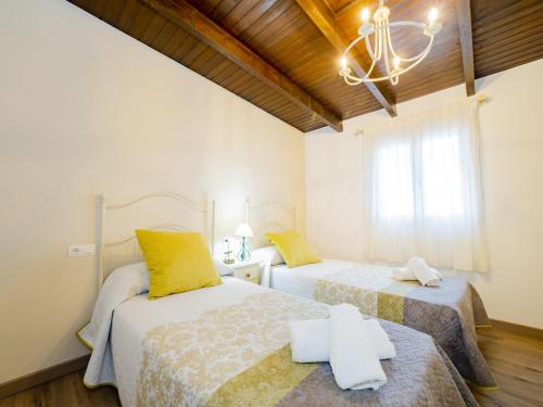 a bedroom with two beds and a chandelier at Cubo's Casa Palmar de la Zarza in Pizarra