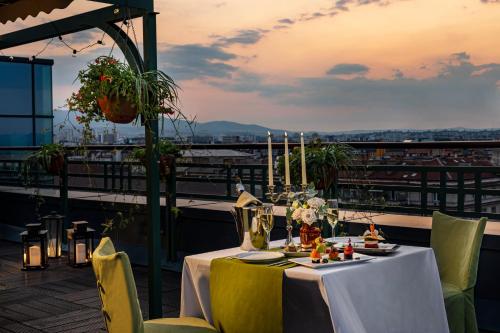 a table on a balcony with a view of a city at Grand Hotel Sofia - Top Location, The Most Spacious Rooms in the City, Secured Underground Parking in Sofia
