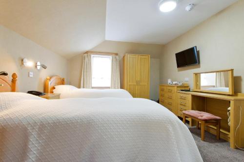 a bedroom with two white beds and a television at Nethercliffe Hotel in Wick