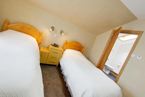 two beds in a small room with a window at Nethercliffe Hotel in Wick