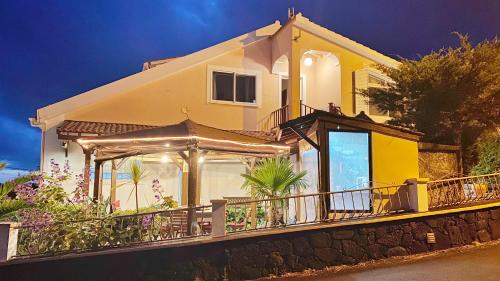 a yellow house with a balcony with flowers at Miradouro da Papalva Guest House - Pico - Azores in São João