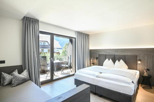 a hotel room with a large bed and a large window at Alpinhotel Keil in Valdaora
