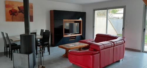 a living room with a red couch and a television at villa neuve ds les monts du lyonnais in Saint-Symphorien-sur-Coise