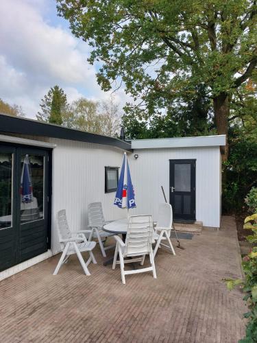 a patio with chairs and a table and umbrella at Huisje Weltevree (nummer 95) in Putten