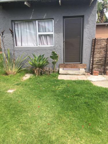 a house with a window and a grass yard at ROOTS BACKPACKERS in Port Elizabeth