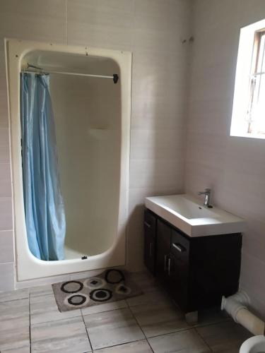 a bathroom with a sink and a shower with a mirror at ROOTS BACKPACKERS in Port Elizabeth