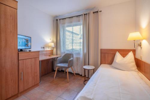 マインツにあるHotel Schottenhofのベッドとデスクが備わるホテルルームです。