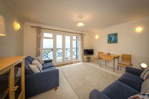 a living room with a blue couch and a table at Seaviews Sovereign Harbour - adults-only apartment in Eastbourne
