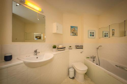 a bathroom with a sink and a toilet and a tub at Seaviews Sovereign Harbour - adults-only apartment in Eastbourne