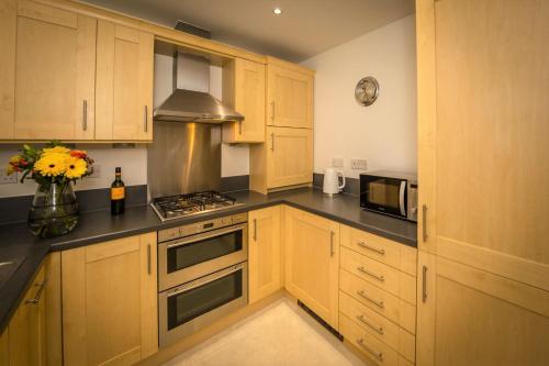 a kitchen with wooden cabinets and a vase of flowers at Seaviews Sovereign Harbour - adults-only apartment in Eastbourne