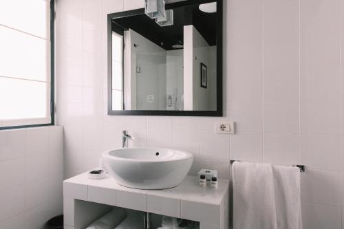 a white bathroom with a sink and a mirror at Aethos Milan in Milan
