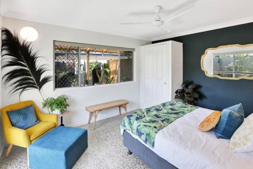 ein Schlafzimmer mit einem Kingsize-Bett und einem gelben Stuhl in der Unterkunft The Tropicana Courtyard in Cairns North