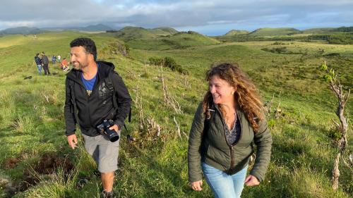 a man and a woman walking on a grassy hill at Miradouro da Papalva Guest House - Pico - Azores in São João