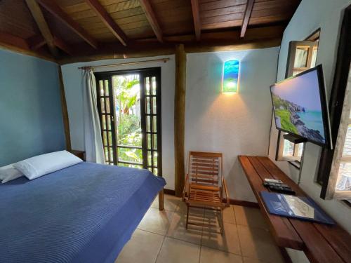 a bedroom with a bed and a flat screen tv at Casa Jardim Bangalos in Paraty